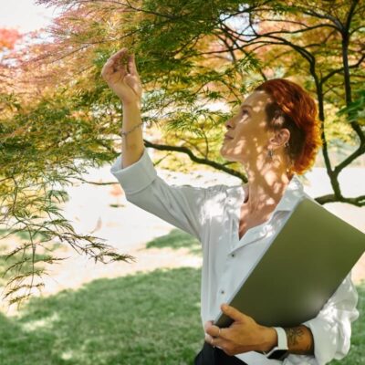 Osoba ogląda liście drzewa w trakcie wykonywania ekspertyzy dendrologicznej.