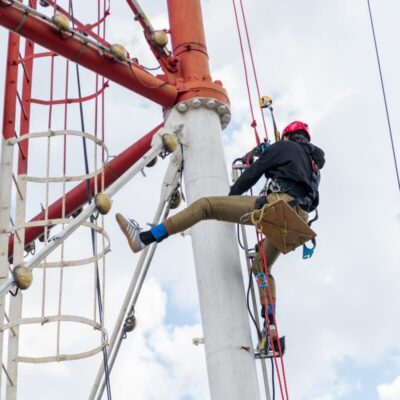 Osoba wykonująca prace wysokościowe na wieży telekomunikacyjnej.