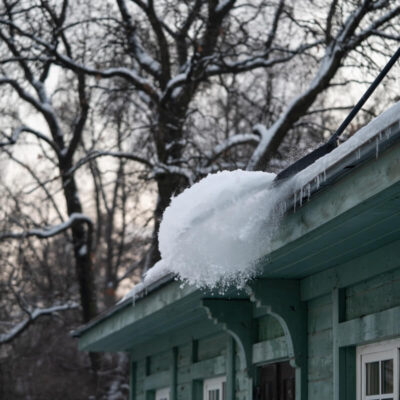 Osoba odśnieża dachy, usuwając śnieg z budynku.